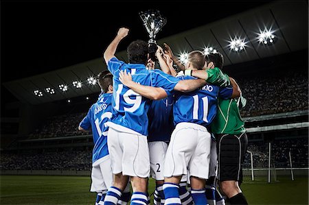 Soccer team cheering with trophy on field Photographie de stock - Premium Libres de Droits, Code: 6113-07310578