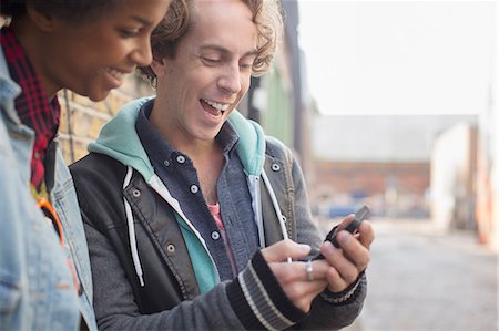 Couple using cell phone on city street Stock Photo - Premium Royalty-Free, Code: 6113-07542464