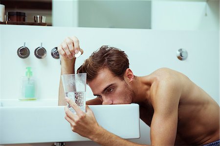 sickness - Hungover man watching effervescent tablets in bathroom Stock Photo - Premium Royalty-Free, Code: 6113-07543010