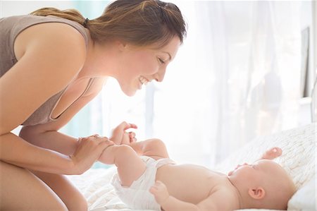 photo adult diaper family - Mother playing with baby girl on bed Stock Photo - Premium Royalty-Free, Code: 6113-07543233