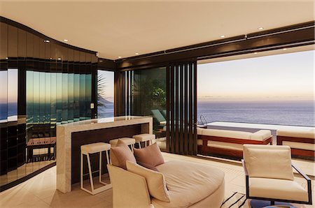 Modern living room and bar overlooking ocean at sunset Stock Photo - Premium Royalty-Free, Code: 6113-07543379