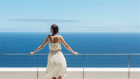 Woman looking at ocean from balcony Stock Photo - Premium Royalty-Free, Code: 6113-07543387