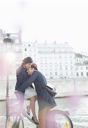 Couple hugging on bicycle along Seine River, Paris, France Stock Photo - Premium Royalty-Free, Code: 6113-07543547