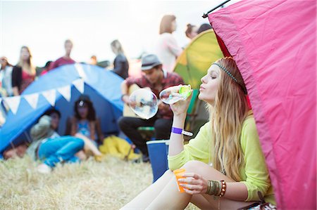 Woman blowing bubbles from tent at music festival Stock Photo - Premium Royalty-Free, Code: 6113-07564761