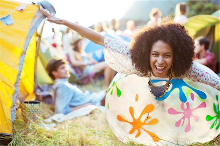 Portrait of playful woman laying on inflatable chair outside tents at music festival Stock Photo - Premium Royalty-Free, Code: 6113-07564886