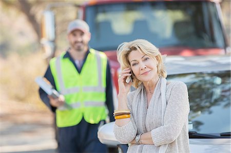Roadside mechanic behind woman on cell phone Stock Photo - Premium Royalty-Free, Code: 6113-07564965