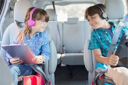picture of happy person in a car - Happy brother and sister with headphones using digital tablets in back seat of car Stock Photo - Premium Royalty-Free, Code: 6113-07565115