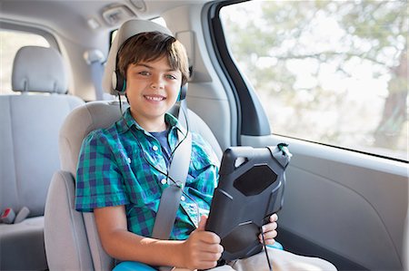 Portrait of happy boy with headphones using digital tablet in back seat of car Stock Photo - Premium Royalty-Free, Code: 6113-07565116