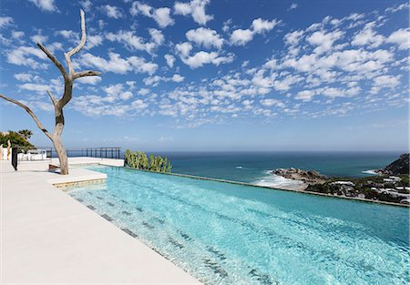 Clouds in blue sky over luxury lap pool overlooking ocean Photographie de stock - Premium Libres de Droits, Code: 6113-07565225