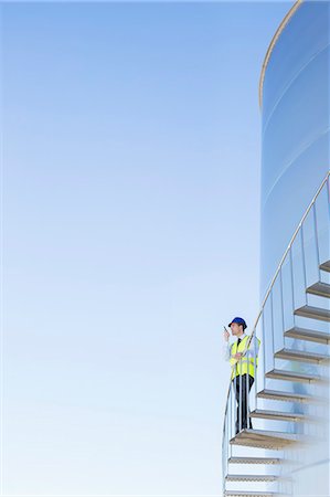 simsearch:6113-07565342,k - Worker using walkie-talkie on winding steps along silage storage tower Stock Photo - Premium Royalty-Free, Code: 6113-07565347