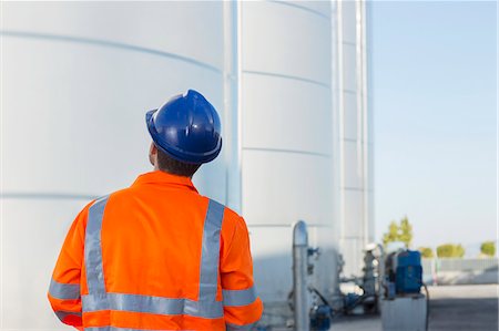 simsearch:6113-07565342,k - Worker looking up at silage storage towers Stock Photo - Premium Royalty-Free, Code: 6113-07565429