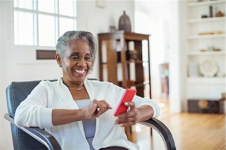simsearch:6113-07543477,k - Happy senior woman text messaging with cell phone in living room Stock Photo - Premium Royalty-Free, Code: 6113-07565571
