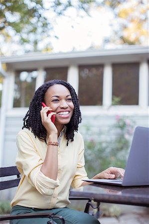 simsearch:6113-07565805,k - Happy woman talking on cell phone at laptop on patio Stock Photo - Premium Royalty-Free, Code: 6113-07565521