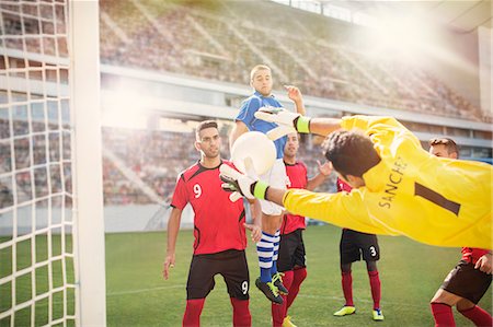 stadium with people outdoor football - Goalie jumping for ball in soccer net Stock Photo - Premium Royalty-Free, Code: 6113-07588867