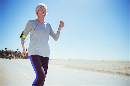 Senior woman jogging on beach boardwalk Stock Photo - Premium Royalty-Free, Code: 6113-07589358