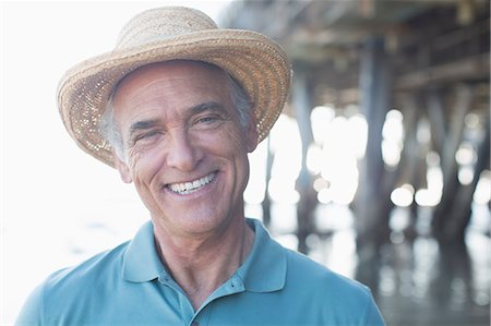 Portrait of smiling senior man in sun hat at beach Stock Photo - Premium Royalty-Free, Code: 6113-07589423