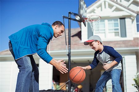 parent and child sports - Father and son playing basketball in sunny driveway Stock Photo - Premium Royalty-Free, Code: 6113-07648819