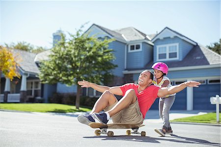 ethnic family walking - Daughter pushing father on skateboard Stock Photo - Premium Royalty-Free, Code: 6113-07648827