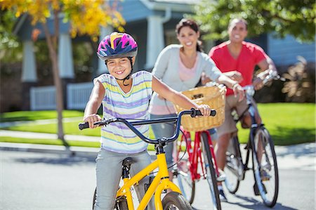 ethnic family exercise - Portrait of smiling family riding bikes in street Stock Photo - Premium Royalty-Free, Code: 6113-07648834