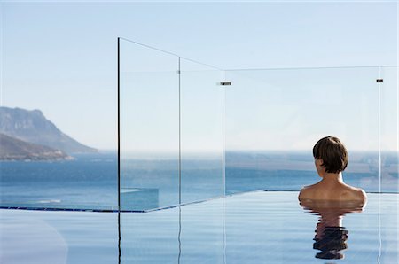 Woman in infinity pool enjoying ocean view Foto de stock - Sin royalties Premium, Código: 6113-07648913