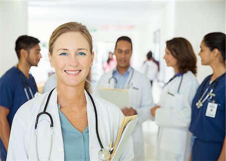 simsearch:6113-07762019,k - Doctor smiling in hospital hallway Stock Photo - Premium Royalty-Free, Code: 6113-07762063