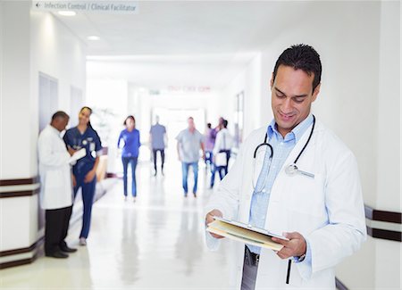 simsearch:649-03771564,k - Doctor reading medical chart in hospital hallway Stock Photo - Premium Royalty-Free, Code: 6113-07762069