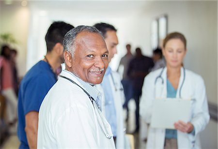 simsearch:6113-07762076,k - Doctor smiling in hospital hallway Stock Photo - Premium Royalty-Free, Code: 6113-07762001