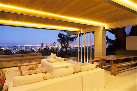 Modern living room overlooking illuminated cityscape at night Stock Photo - Premium Royalty-Free, Code: 6113-07790473