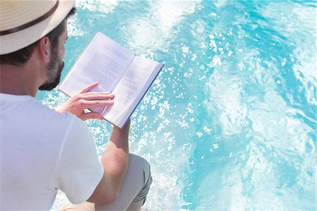 simsearch:6113-07790529,k - Man reading book over swimming pool Stock Photo - Premium Royalty-Free, Code: 6113-07790548