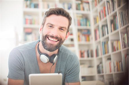 Smiling man using digital tablet in living room Stock Photo - Premium Royalty-Free, Code: 6113-07790506