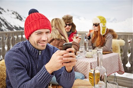 Man using cell phone on snowy balcony Stock Photo - Premium Royalty-Free, Code: 6113-07790661