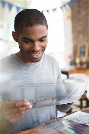 Businessman examining transparency at lunch meeting in cafe Stock Photo - Premium Royalty-Free, Code: 6113-07790846