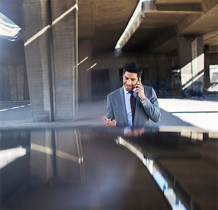 Businessman talking on cell phone in parking garage Stock Photo - Premium Royalty-Free, Code: 6113-07790874