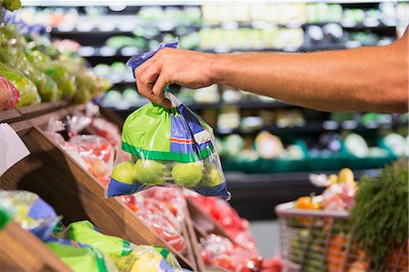 shopping in vegetable & fruits - Man holding bag of produce in grocery store Stock Photo - Premium Royalty-Free, Code: 6113-07791087