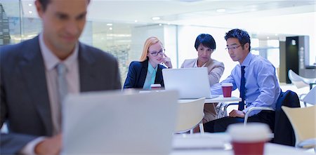 Business people gathered around laptop in office building Stock Photo - Premium Royalty-Free, Code: 6113-07791246