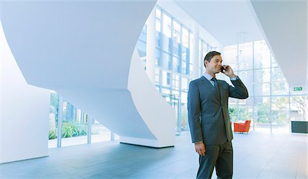 Businessman talking on cell phone in office building Stock Photo - Premium Royalty-Free, Code: 6113-07791228