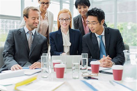 Business people gathered around laptop in office building Stock Photo - Premium Royalty-Free, Code: 6113-07791354