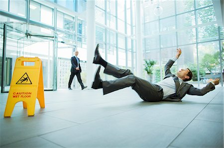 Businessman slipping on floor of office building Stock Photo - Premium Royalty-Free, Code: 6113-07791399
