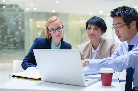 simsearch:6122-07706325,k - Business people gathered around laptop in office building cafe Stock Photo - Premium Royalty-Free, Code: 6113-07791326