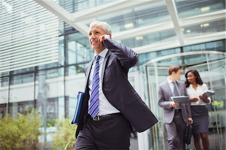 simsearch:649-07560129,k - Businessman talking on phone while walking out of office building Foto de stock - Sin royalties Premium, Código: 6113-07791463