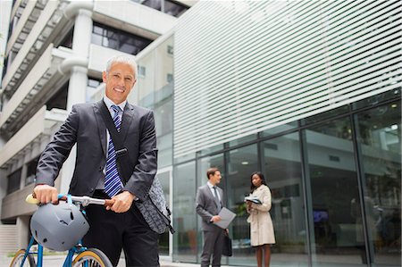 Businessman walking bicycle outside of office building Stock Photo - Premium Royalty-Free, Code: 6113-07791434