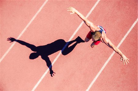 simsearch:6113-07730460,k - Track and field athlete jumping on track with arms outstretched Stock Photo - Premium Royalty-Free, Code: 6113-07730461