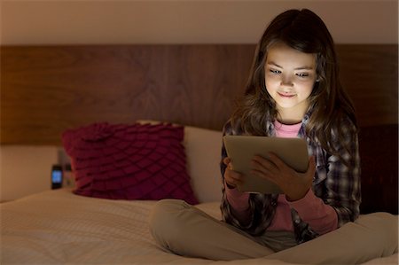 Girl using digital tablet on bed Stock Photo - Premium Royalty-Free, Code: 6113-07730572