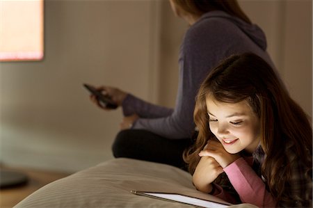 Girl using digital tablet on bed Stock Photo - Premium Royalty-Free, Code: 6113-07730584