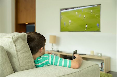 Boy watching television in living room Stock Photo - Premium Royalty-Free, Code: 6113-07730519