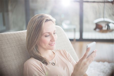 simsearch:6113-07731119,k - Woman using cell phone on sofa Stock Photo - Premium Royalty-Free, Code: 6113-07730752