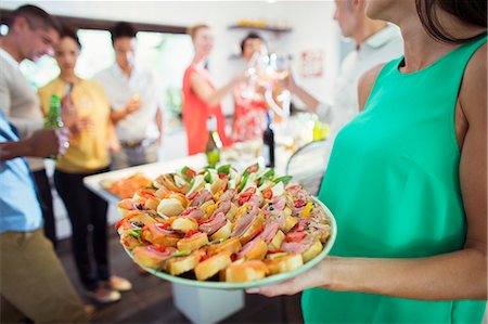 Woman serving tray of food at party Photographie de stock - Premium Libres de Droits, Code: 6113-07730825