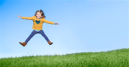 Girl jumping for joy on grassy hill Stock Photo - Premium Royalty-Free, Code: 6113-07731195