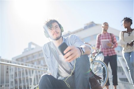 flare - Man listening to headphones on city street Stock Photo - Premium Royalty-Free, Code: 6113-07731389
