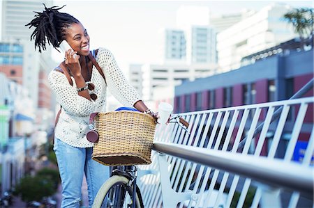 person in a basket of a bike - Woman talking on cell phone on city street Stock Photo - Premium Royalty-Free, Code: 6113-07731404